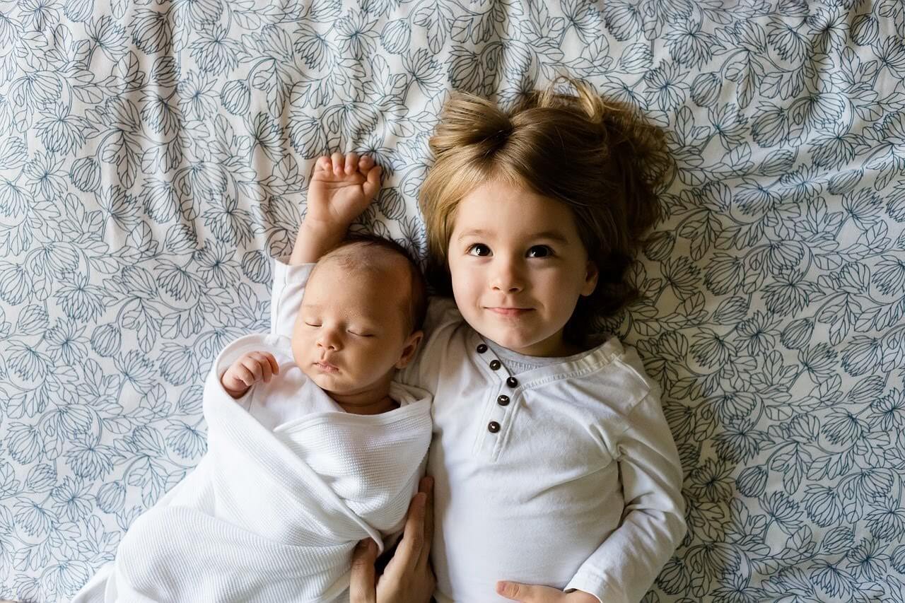 幼児と赤ちゃんが一緒に寝っ転がっている写真